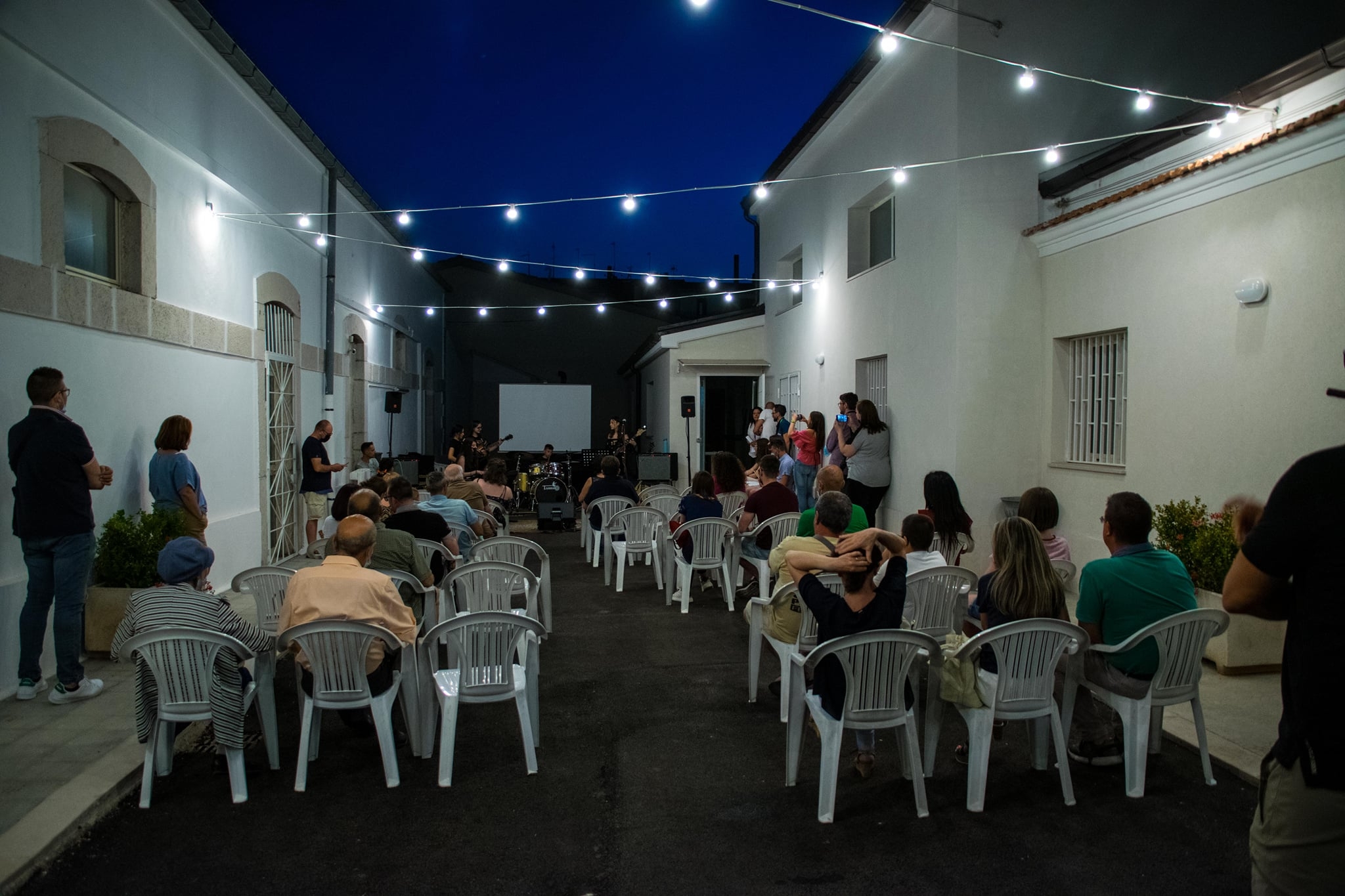 Cortile esterno di sera con seie e persone, durante un evento serale