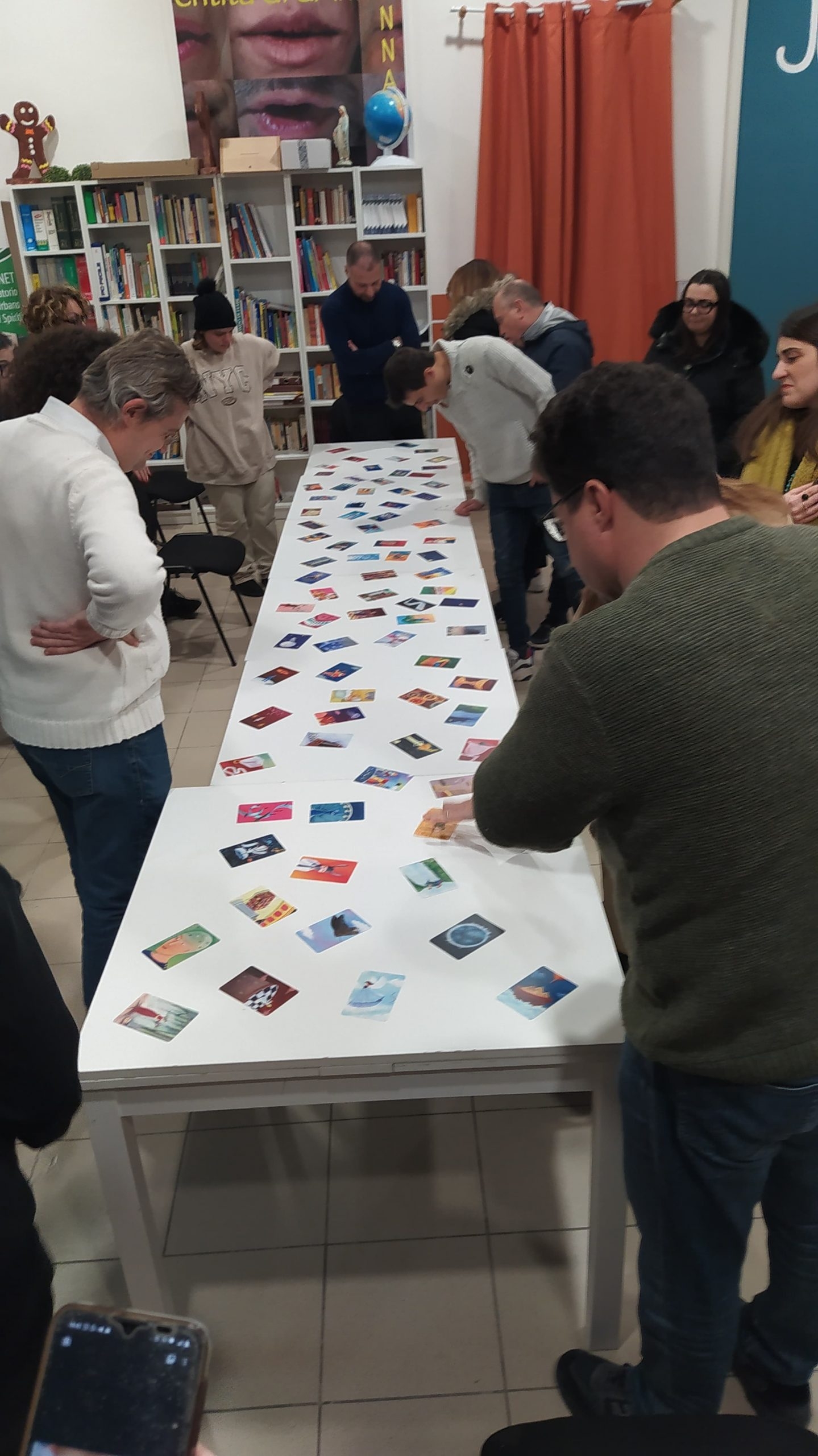 Gruppo dei partecipanti intorno al tavolo sul quale sono state disposte le carte del gioco Dixit. L'attività è fatta in occasione del laboratorio "Statt Citt - Diamo voce ai giovani" presso il Nodo Galattica di Cisternino, 15 gennaio 2024