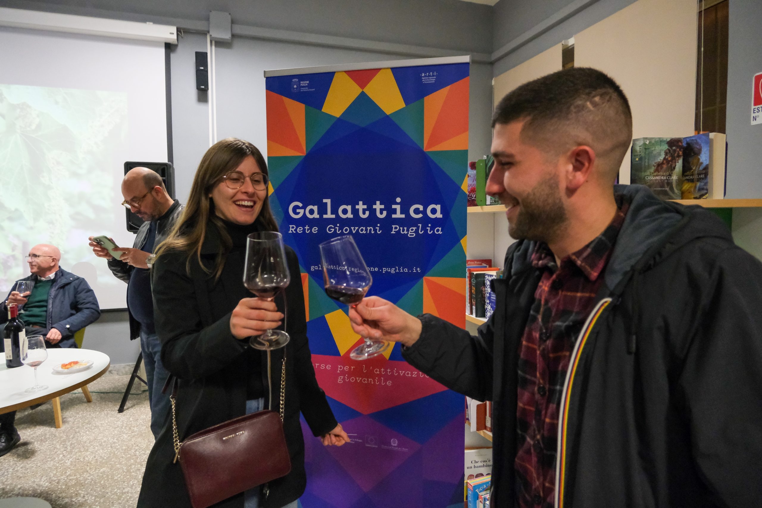 due giovani brindano durante l'evento "Enologicamente parlando" presso il Nodo Galattica di Trepuzzi