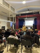 ragazzi seduti e persona in piedi che parla