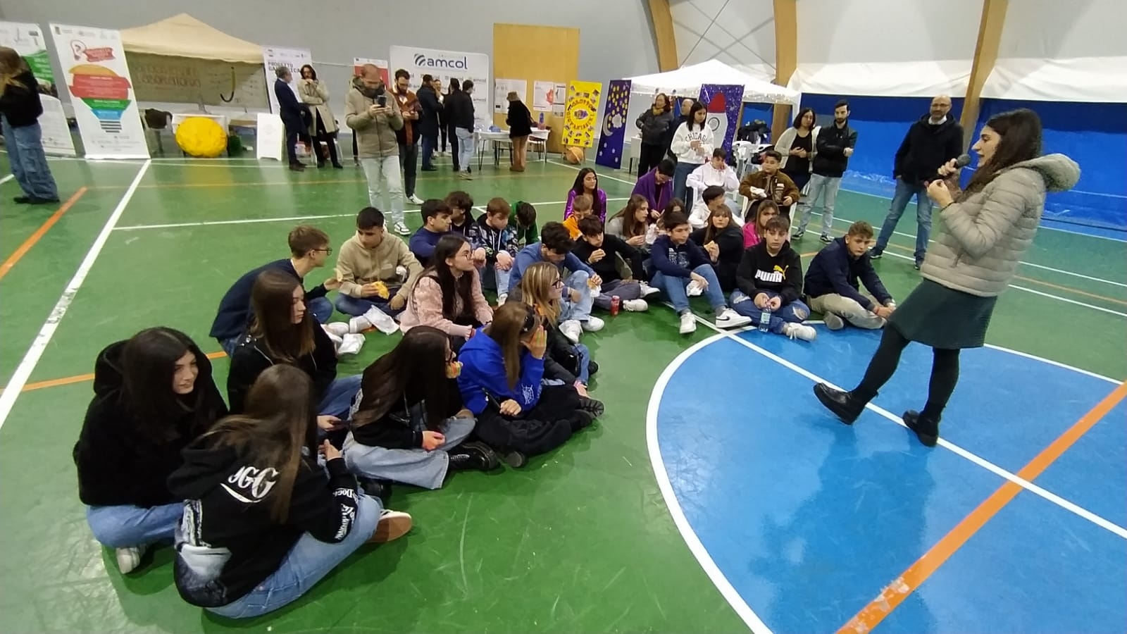 Giovani seduti a terra all'interno del Palasport dove si è tenuta l'Inaugurazione del Nodo Galattica di Cisternino, 18 novembre 2023