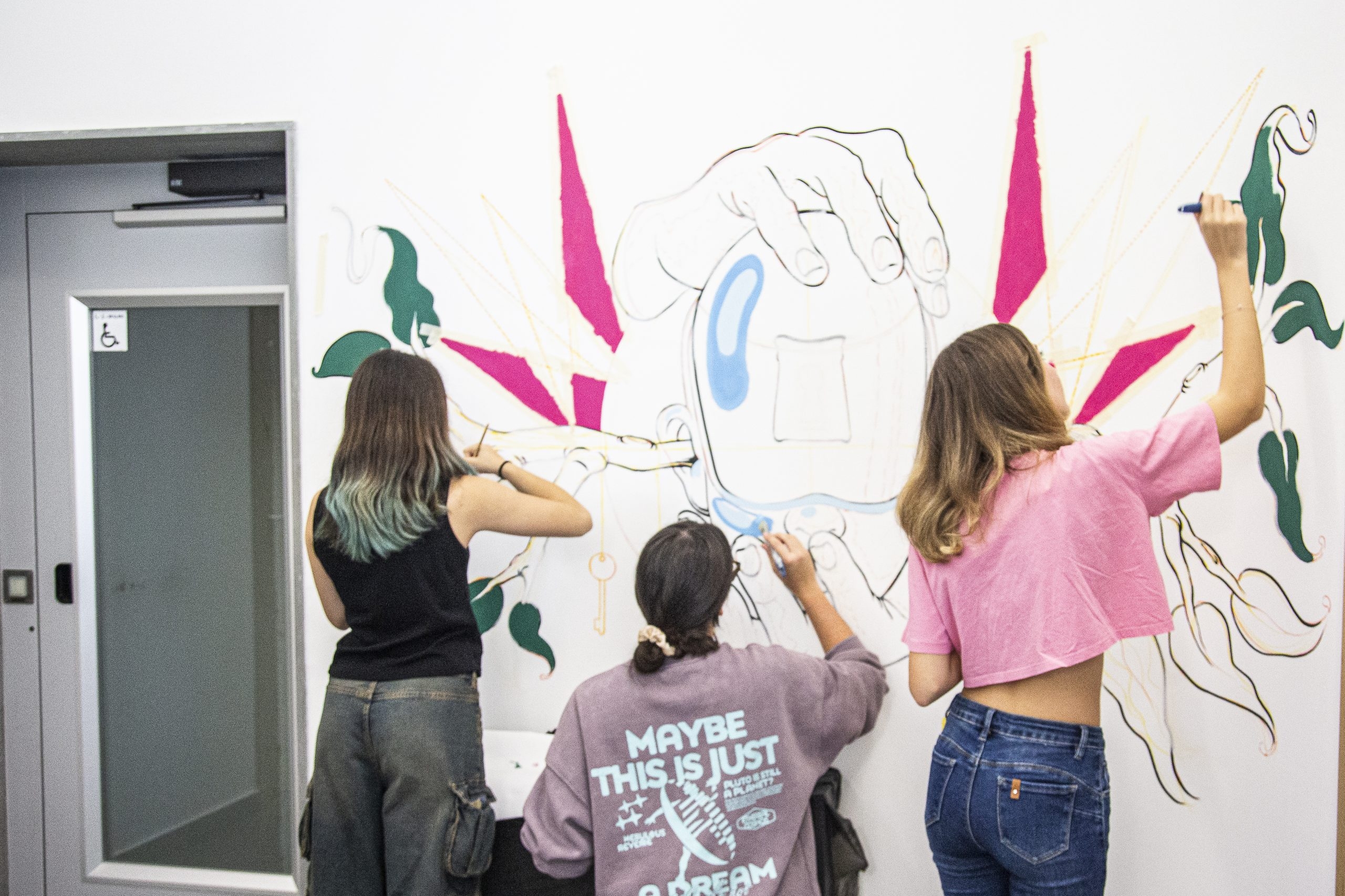 Ragazze dipingono con colori un disegno sul muro nella sede di Galattica del nodo di Mesagne.