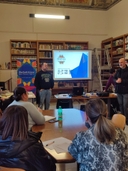 gruppo di giovani seduti ad un tavolo mentre ascoltano il formatore durante il workshop di video maker