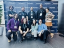 Il team di Radio Luoghi Comuni in posa al Womex 2024 davanti al backdrop ufficiale dell'evento