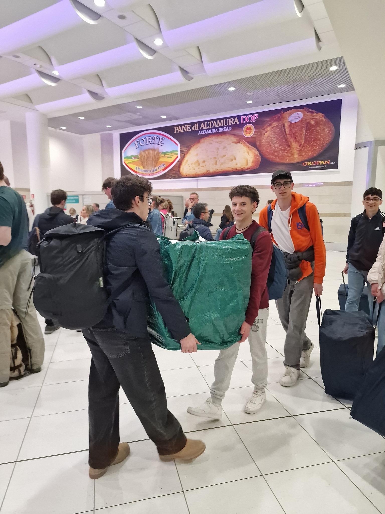 L'immagine cattura il momento dell’arrivo del Team Remate in aeroporto, durante una trasferta per partecipare a un evento innovativo. I membri del team trasportano bagagli e materiali essenziali per il progetto