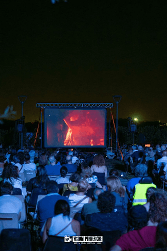 Persone che guardano un film al cinema all'aperto durante il Festival Visioni Periferiche a Bitonto