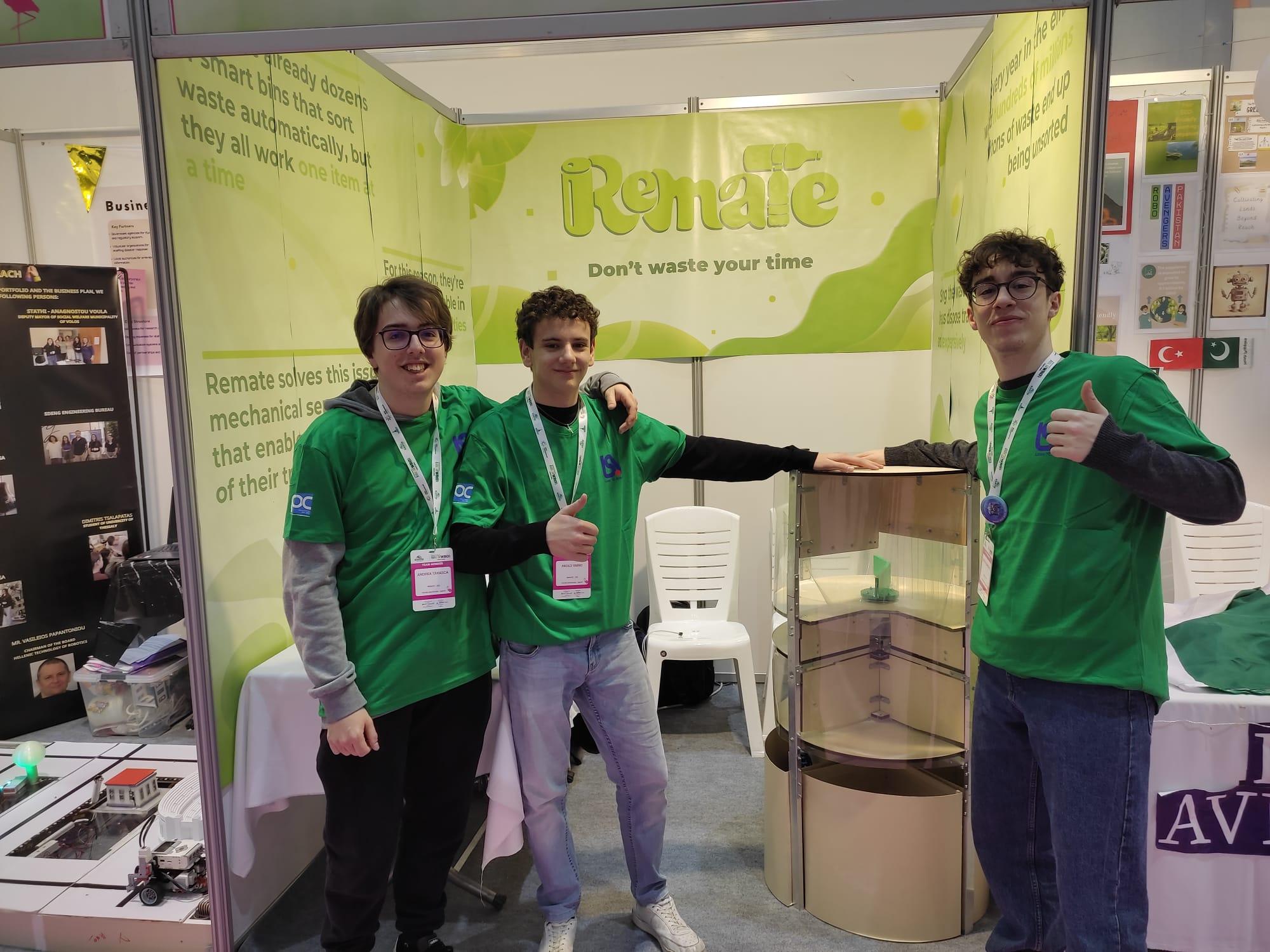 I membri del Team Remate mostrano con orgoglio il loro prototipo di cestino intelligente presso il loro stand espositivo.