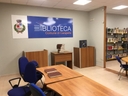 stanza con tavolo, sedie e banner sulla parete con su scritto "biblioteca"