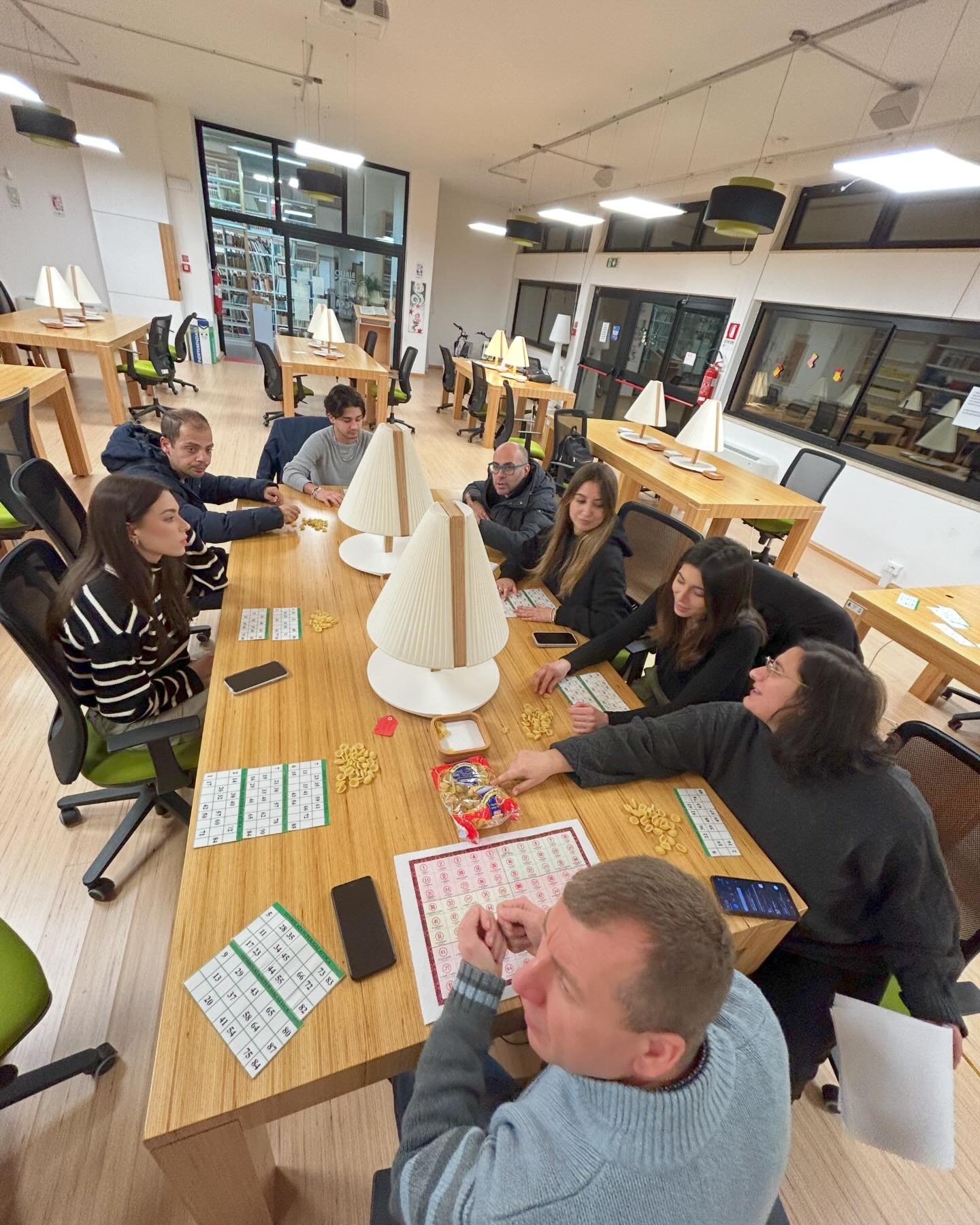 Gruppo di persone gioca a tombola nella sala lettura di una biblioteca