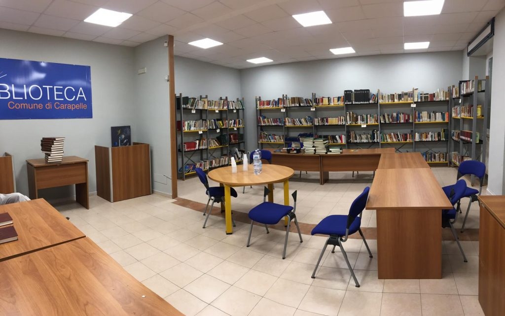 stanza con tavolo e sedie al centro e scaffali con libri sulle pareti