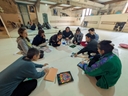 Secondo incontro del corso di composizione coreografica Sette ragazze e due ragazzi, seduti in cerchio sul pavimento di una sala di danza, osservano le immagini di un libro proposte da una di loro.