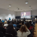 Attività di cineforum, in foto il momento in cui viene proiettato il film "Crescendo" Persone sedute in una grande sala con un telo su cui viene proiettato un film