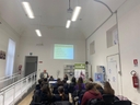 Incontro "Prevenzione e futuro: falsi miti e credenze sulle droghe" In una sala giovani seduti, visti di spalle, ascoltano un uomo in piedi che parla e sullo sfondo in alto viene proiettata una slide sul muro bianco.