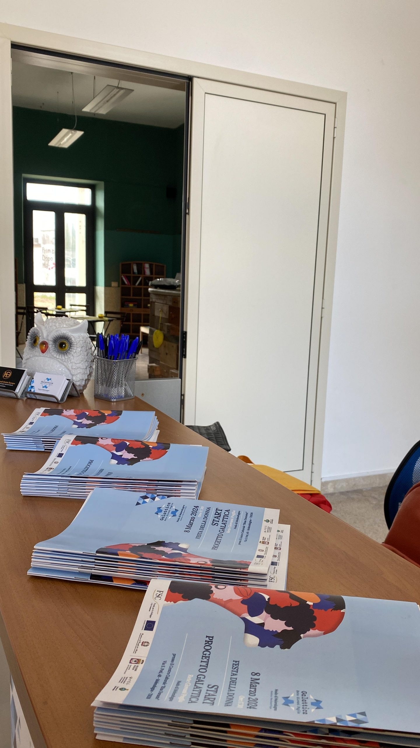 Bancone in legno con brochure e porta aperta in un muro bianco.