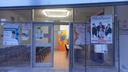 Spazio del nodo di Taviano-entrata Porta a vetri di entrata nello spazio del nodo di Taviano. All'esterno un cartellone dell'evento dei Malfattori che informa che presso quello spazio si possono comprare le prevendite. Appesi alla porta ci sono altre locandini di eventi passati di Galattica e non. Dalla porta si intravede un tavolo con davanti tante sedie disposte a platea e davanti il tavolo il roll-up di Galattica.