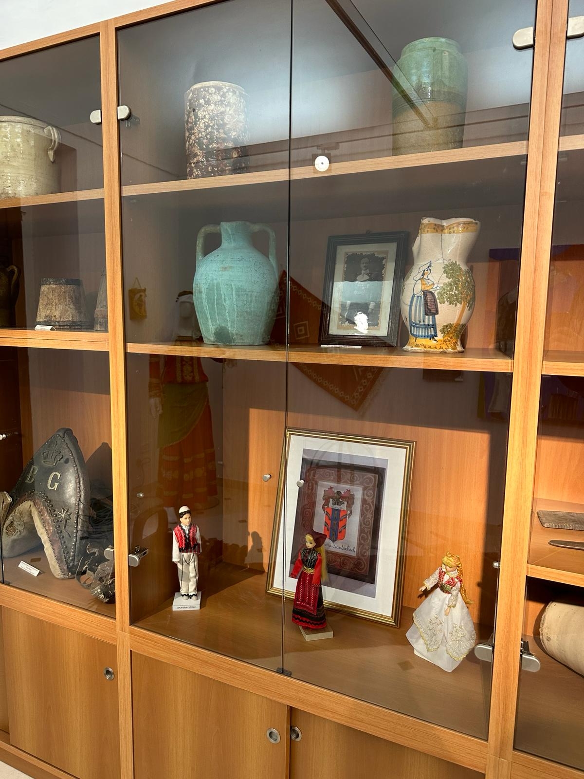 Teca di vetro con in basso sportelli di legno. Al suo interno cimeli, vasi e statuette in abiti tipici.
