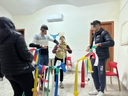 Momento di aggregazione allestendo lo spazio  4 ragazzi di cui due ragazzi e una ragazza che tengono alcune stogge colorate in una stanza con le pareti chiare