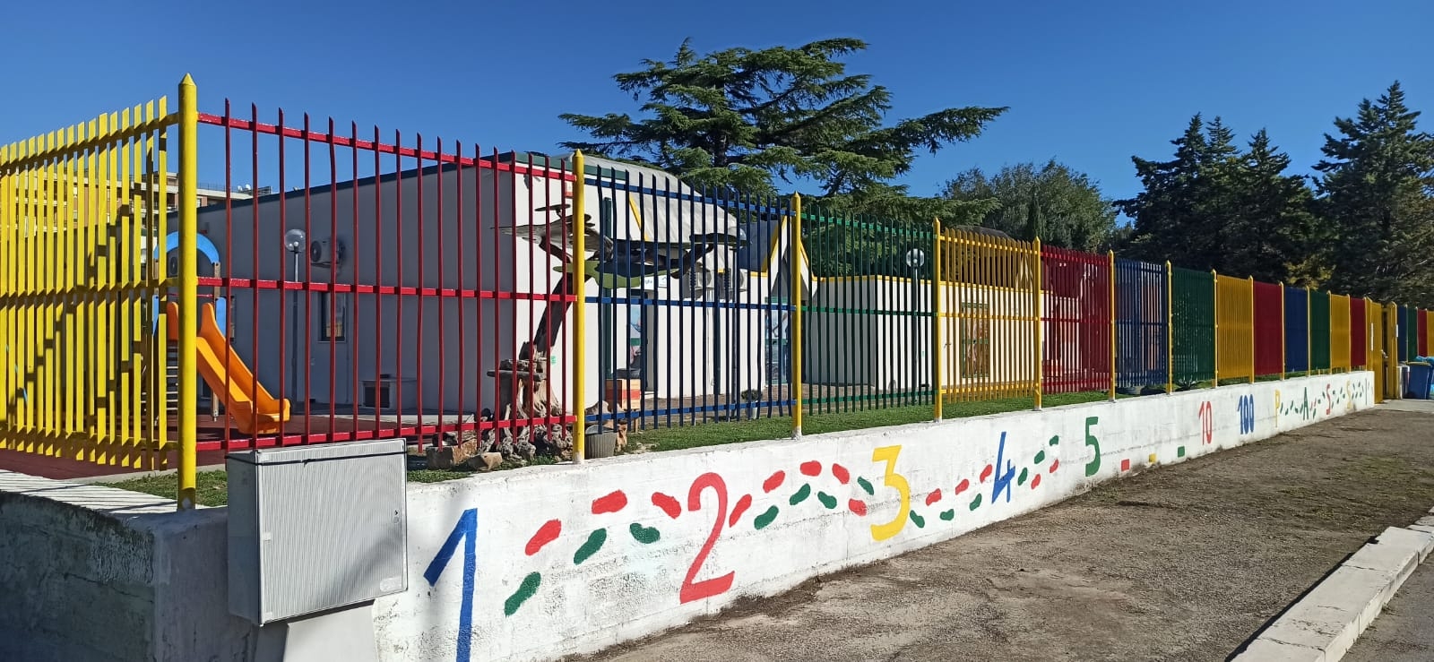 Mura bianche con recinzione in ferro colorata e struttura bianca sullo sfondo