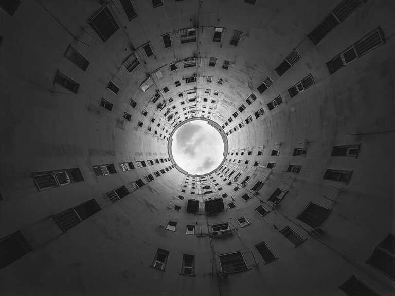 Scatto vincitore di Nicola Abbrescia al Bari Photo Contest Visione circolare dal basso di un edificio, con una finestra aperta verso il cielo