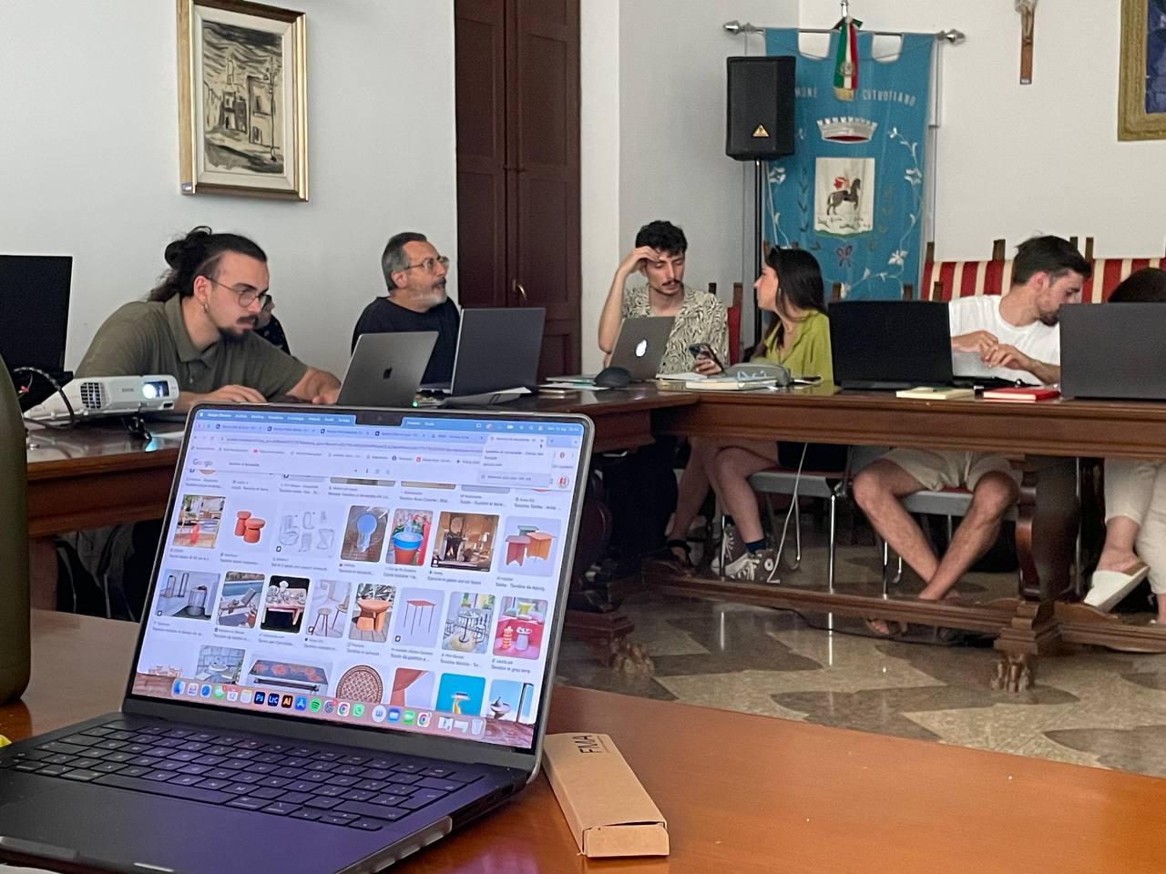 "A New Local Age Academy": Un Progetto di Design Sostenibile Giovani seduti con computer mentre lavorano a un progetto