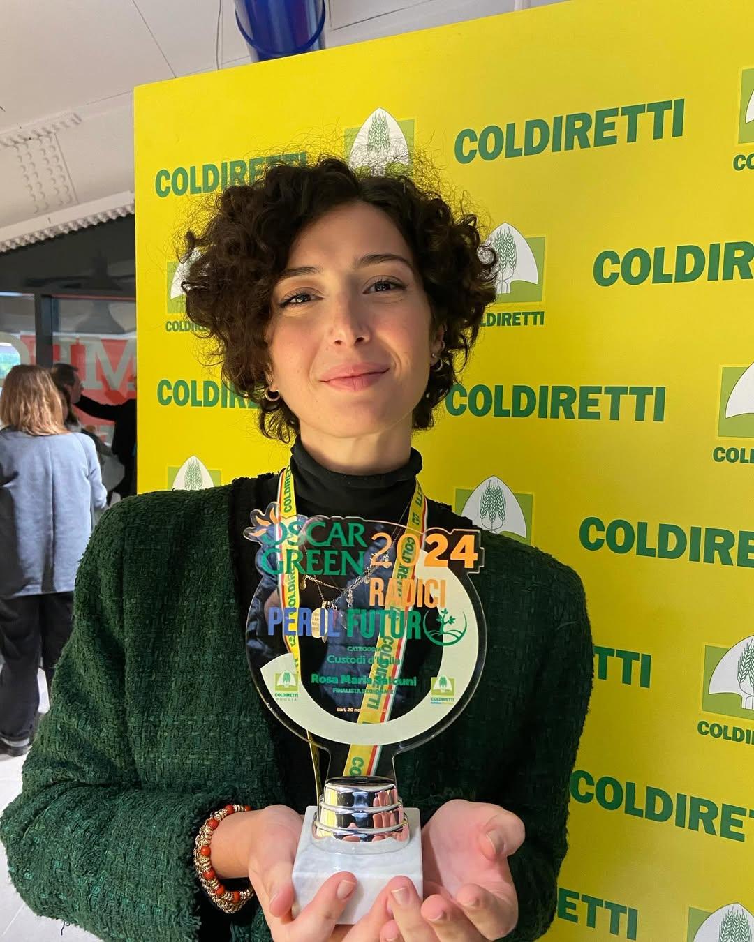 giovane donna tiene in mano il premio Oscar Green 2024,