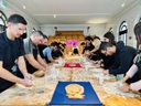 Workshop di panificazione collettiva con Terzo Paesaggio e Madre Project Partecipanti impegnati in un laboratorio di panificazione, lavorando l'impasto su lunghe tavolate in un ambiente luminoso e accogliente
