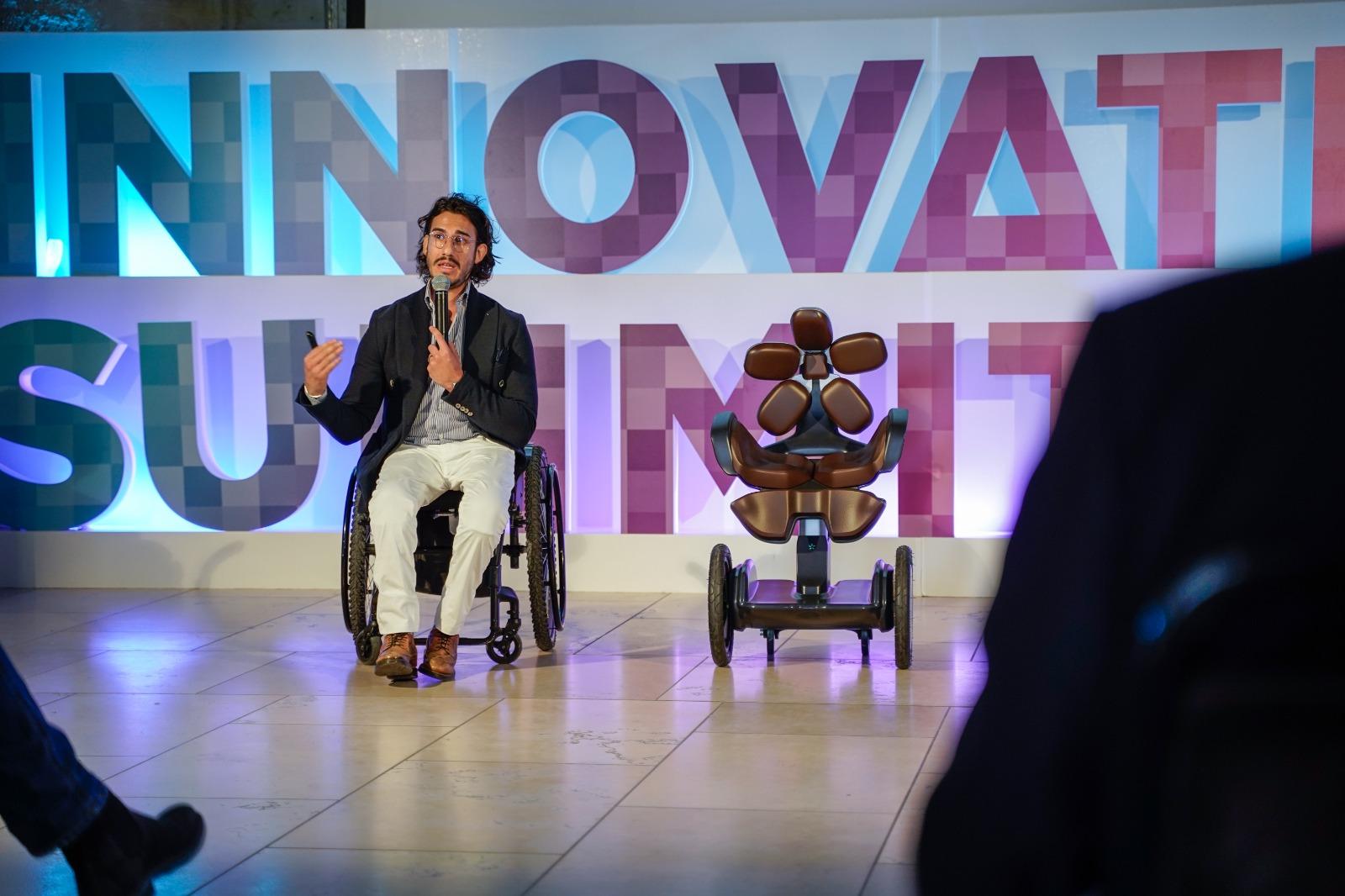 Alessio Sansò al Taranto Innovation Summit Alessio Sansò parla al Taranto Innovation Summit accanto a un dispositivo tecnologico di mobilità. Sullo sfondo, la scritta INNOVATION SUMMIT illuminata.
